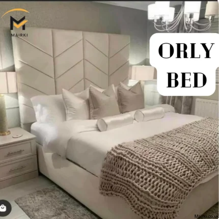 Elegant bedroom with an Orly Bed featuring a high chevron-patterned headboard, white bedding, decorative pillows, and a taupe knitted throw.