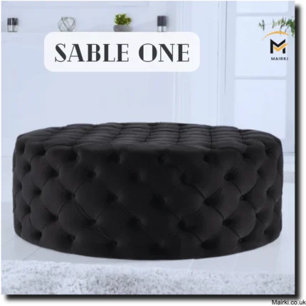 Round black tufted ottoman in a minimalist room with decorative items and a logo for Mairki.