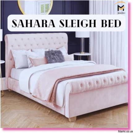 A plush, light pink sleigh bed with tufted details in a stylish bedroom setting with dark walls and gold accents.