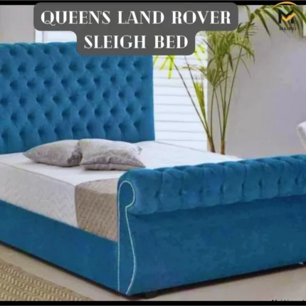 Blue tufted sleigh bed with white bedding and gray pillows, set in a modern room with a potted plant.