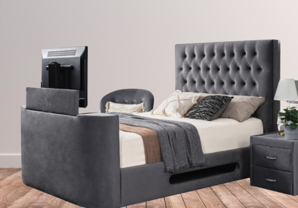 Luxurious grey velvet bed with button-tufted headboard and built-in TV lift, surrounded by neutral bedding and wooden flooring.