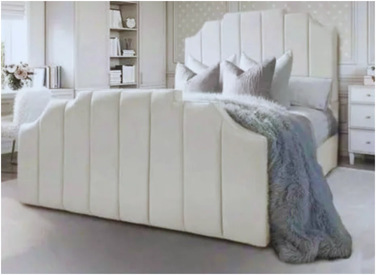 Bedroom with a super king size bed featuring cream vertical-paneled headboard and footboard, gray pillows, and a textured blanket, set within a light-toned room.