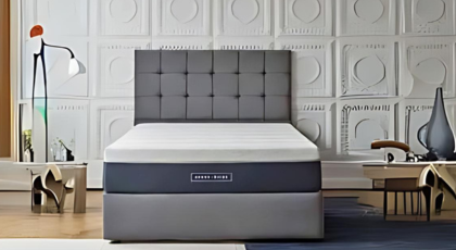 Modern bedroom with a grey divan-bed and a tufted headboard, against a decorative panelled wall.