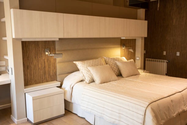 Bedroom with overbed storage unit above the bed and beige decor.