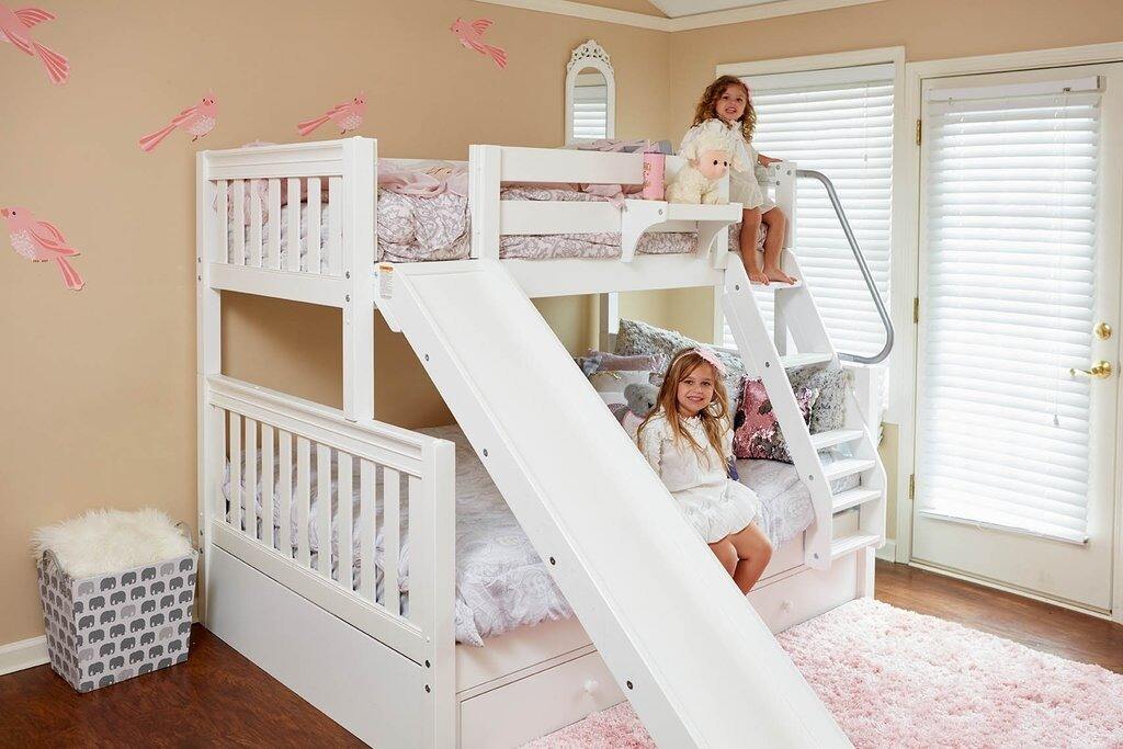 Children's bedroom with a white kids bed with slide and pink bedding.